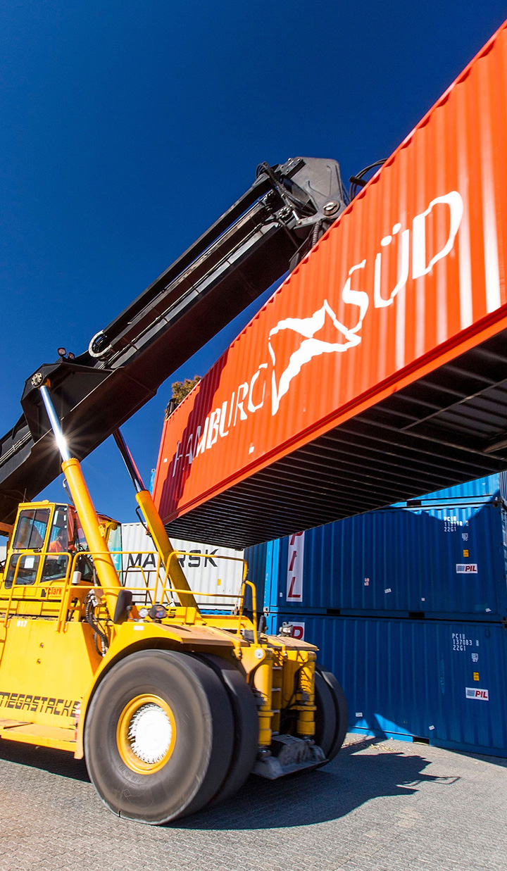 Yellow crane lifting an orange container.