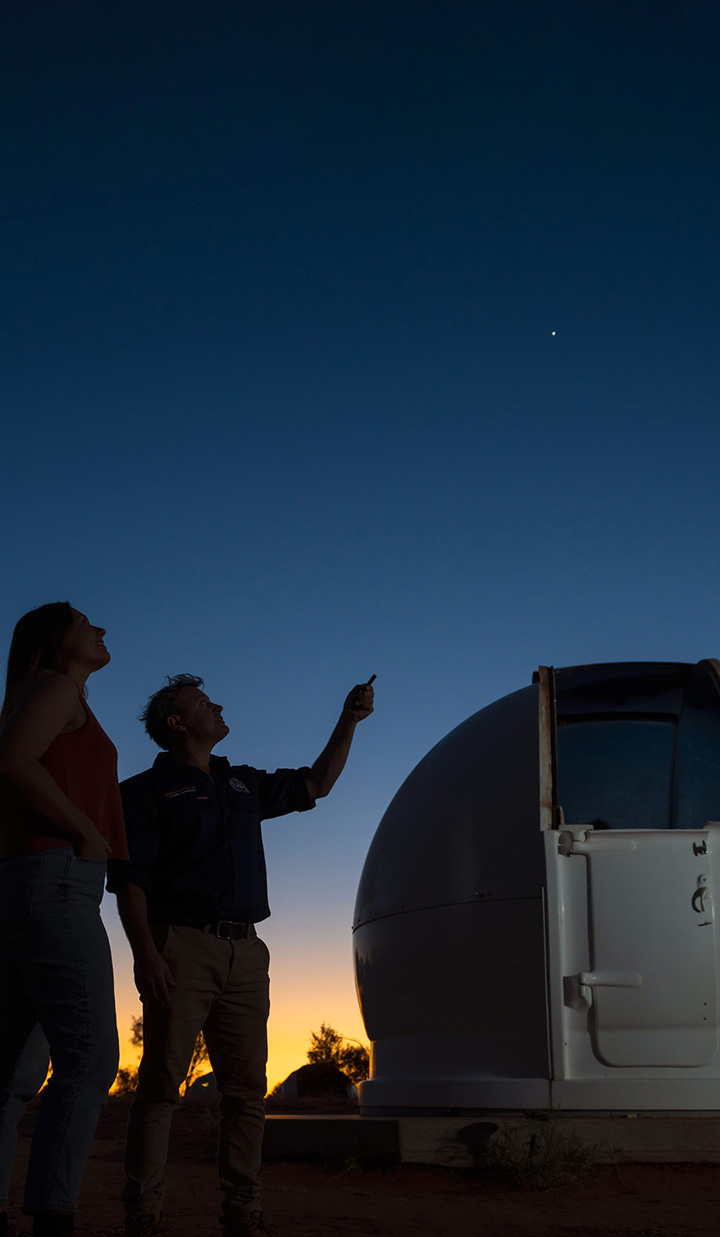 two people stargazing beside observatory at dusk