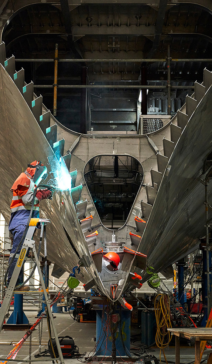 Worker welding inside metal ship structure.