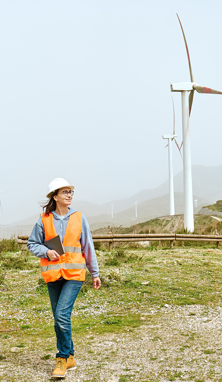 female-engineer-walking-through-wind-farm-with-tablet