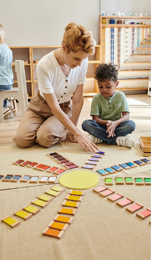 Teacher talking to young boy near a colour wheel