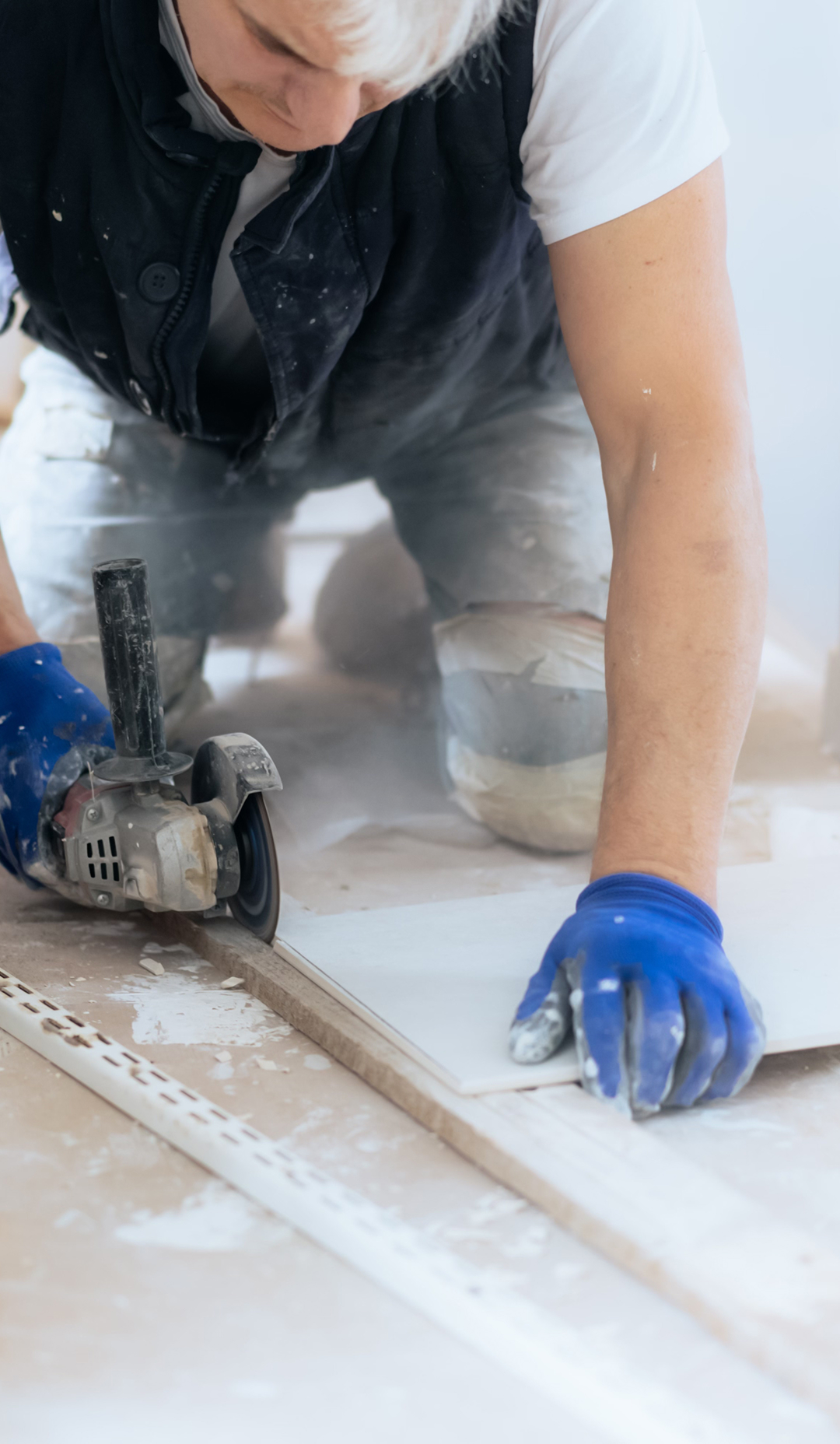 Tiler or construction worker cutting tiles indoors with power tool