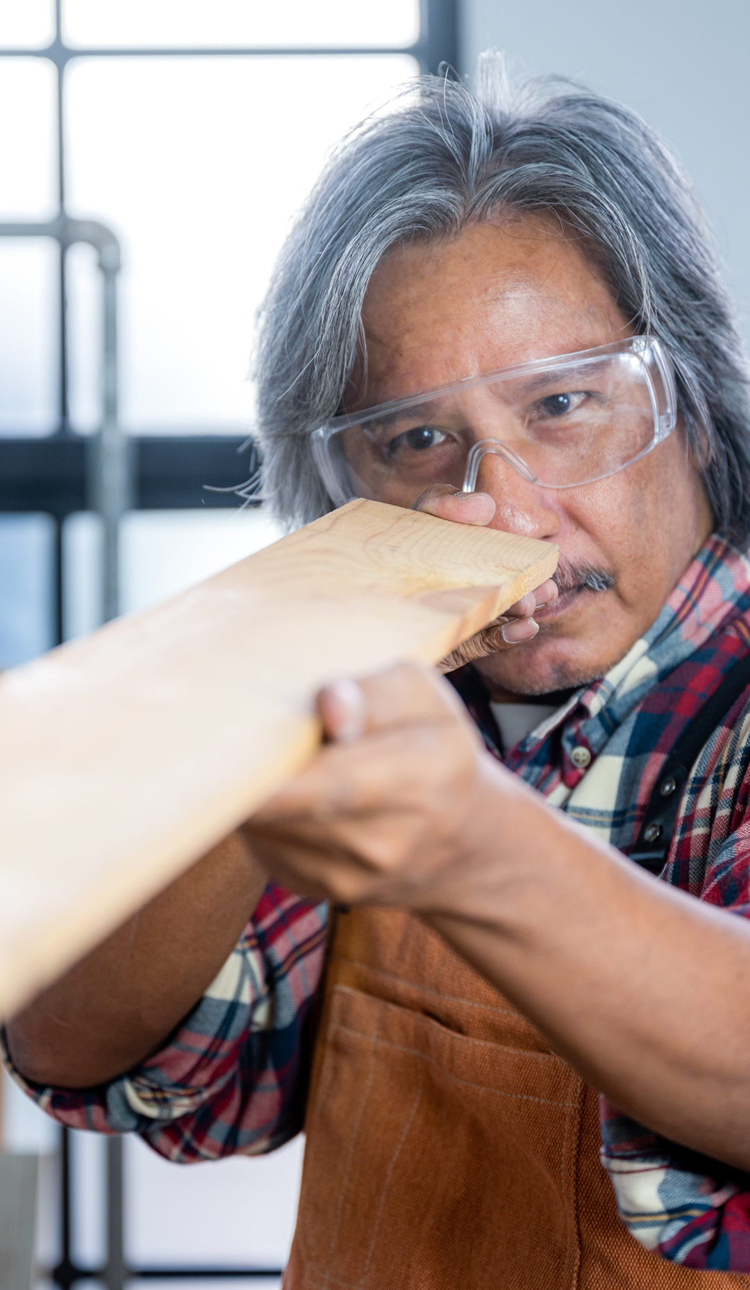 Older cabinetmaker examining a timber board in a workshop