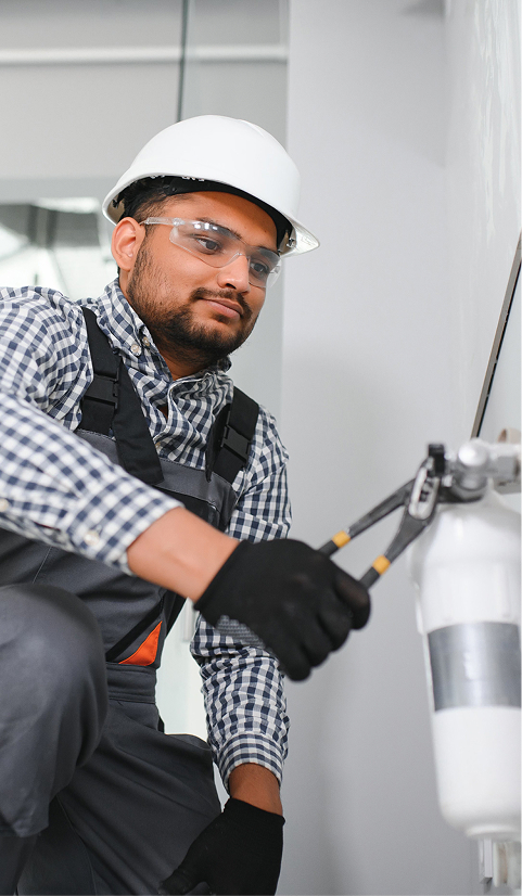 Plumber wearing a hard hat and safety glasses installing a wall-mounted water filter inside a modern home