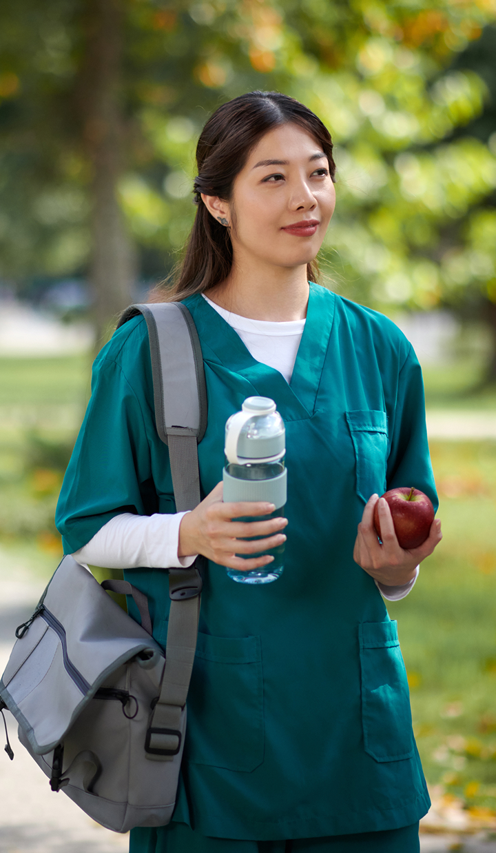 Nurse walking around the campus with a bottle of water and an apple