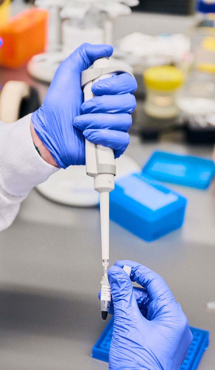 gloved hands handling pipette and sample tube in laboratory