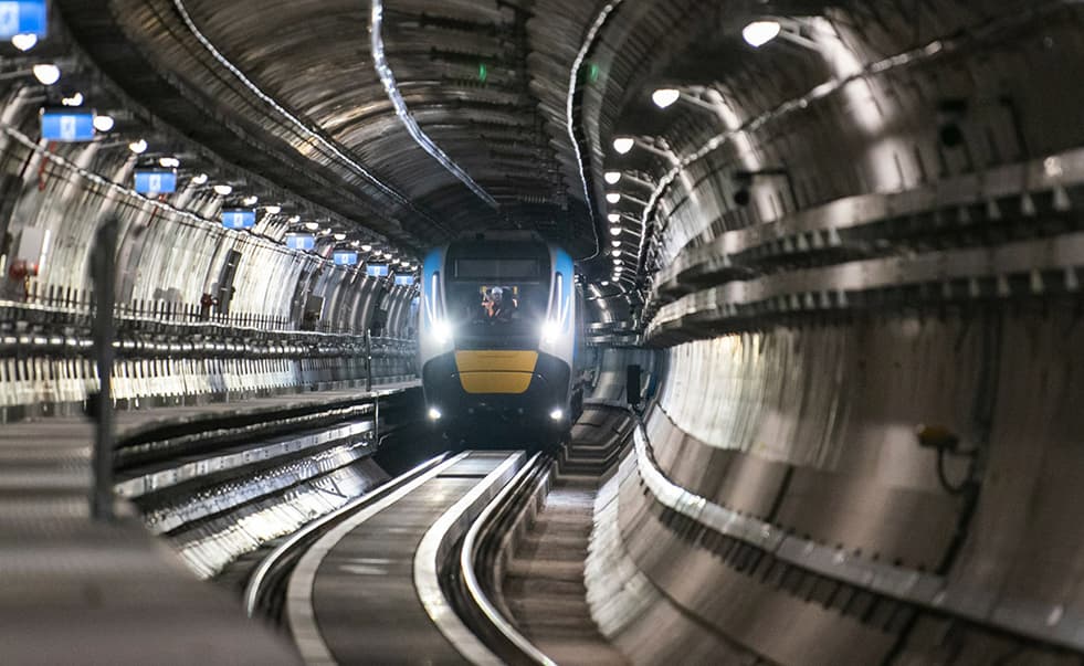 Metro Train running inside a tunnel with lights on shining along the rails