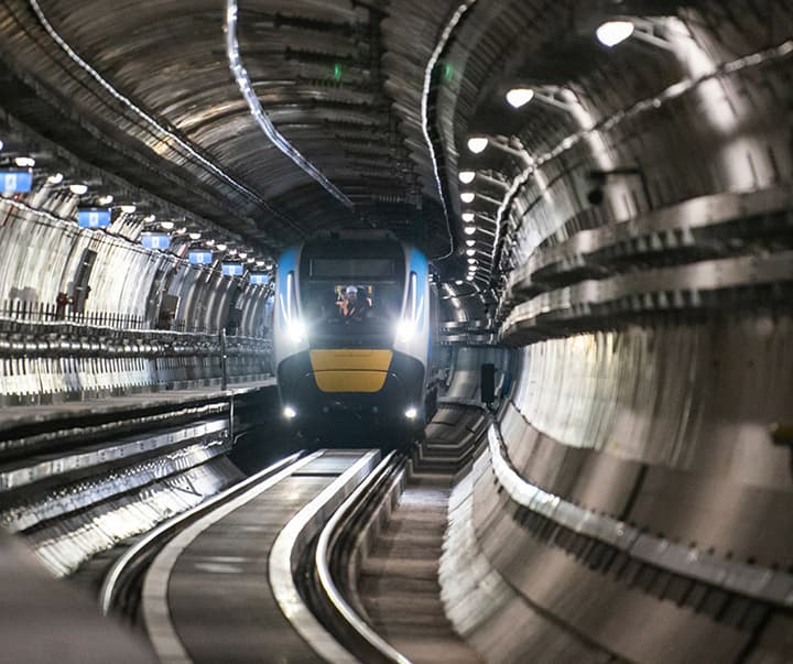 Metro Train running inside a tunnel with lights on shining along the rails