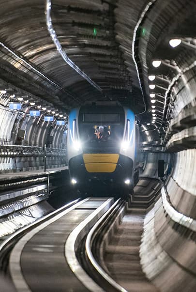 Metro Train running inside a tunnel with lights on shining along the rails