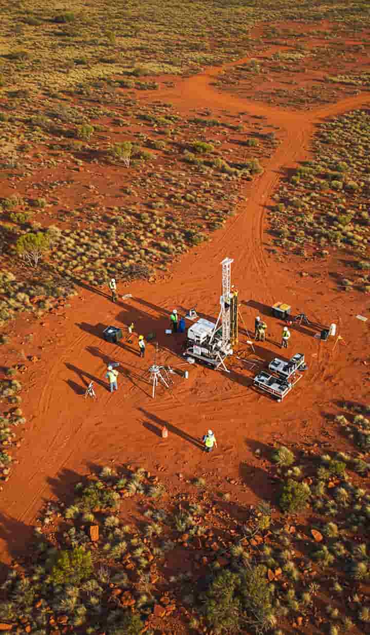 Geoscientists conducting a mineral exploration survey in the Australian outback, using drones, satellite mapping tablets, and portable drilling rigs, expansive landscape, vibrant natural colours.