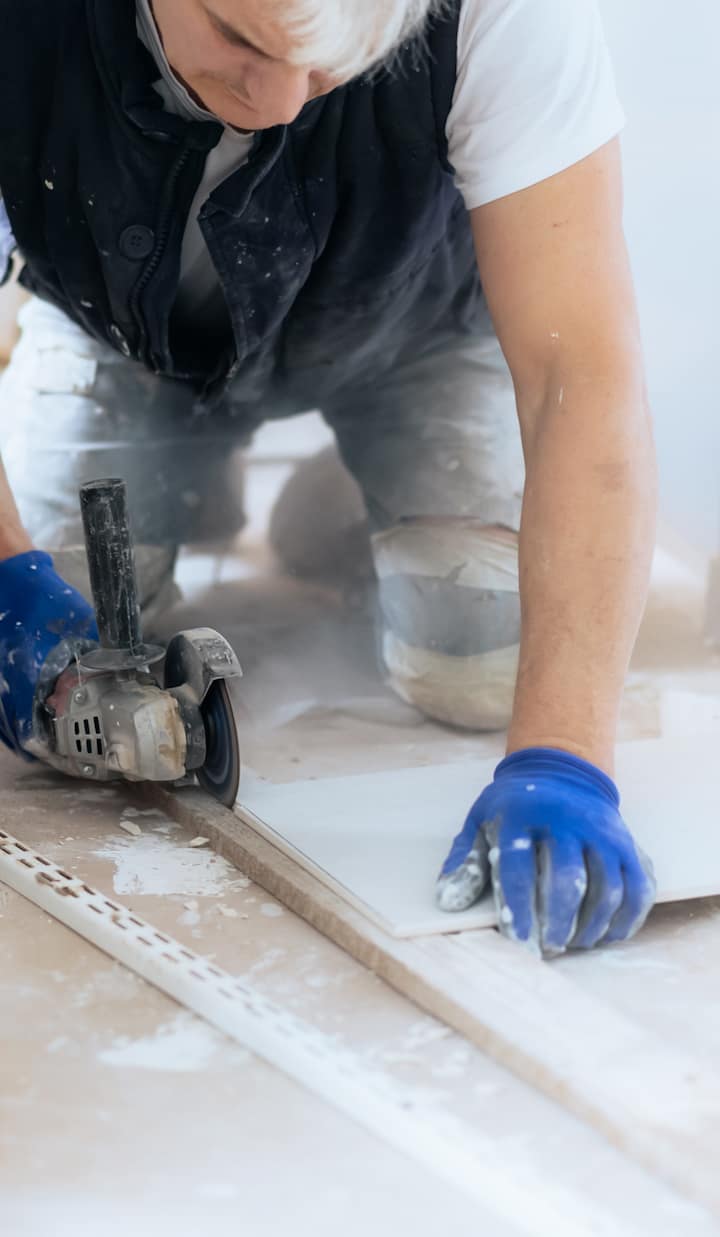 Tiler or construction worker cutting tiles indoors with power tool