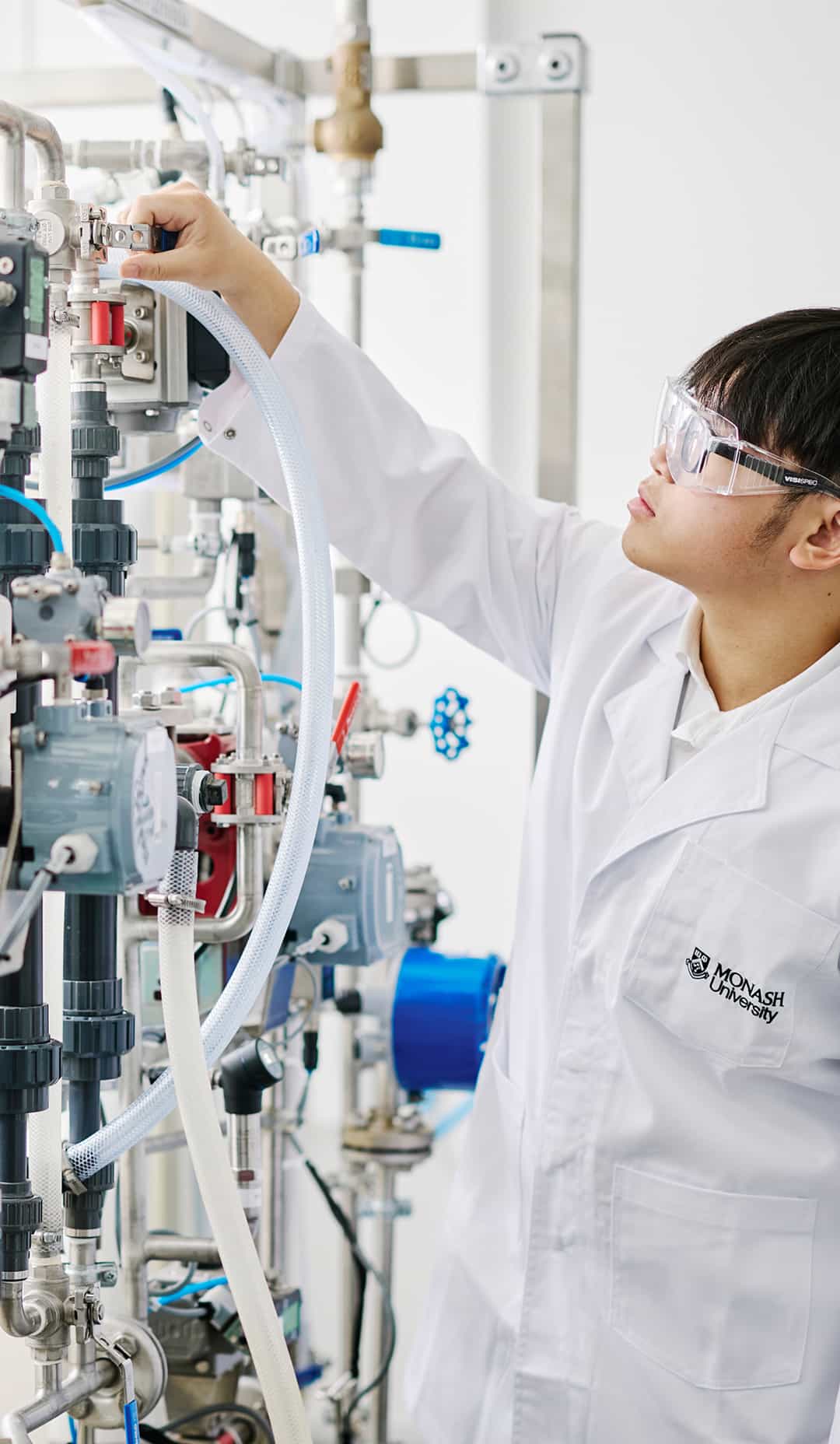 A Monash University student in a white coat learning how to operate a machine