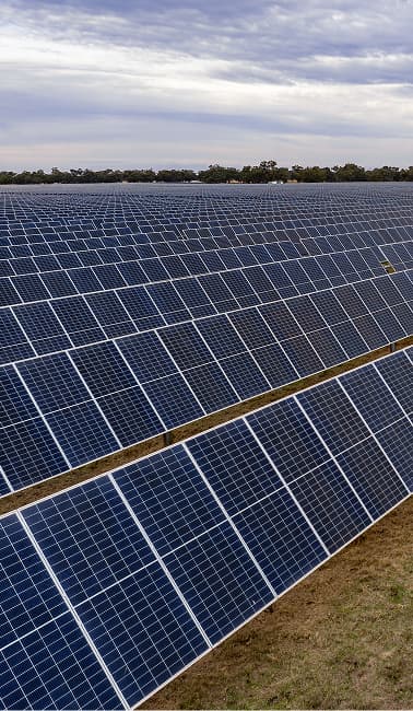 A large solar farm with rows of solar panels under a cloudy sky.