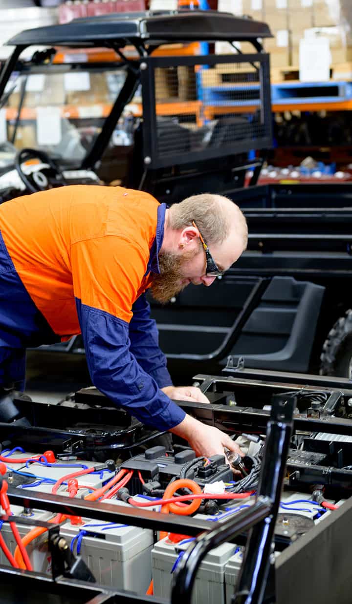 A man bent over a workstation working on car batteries.