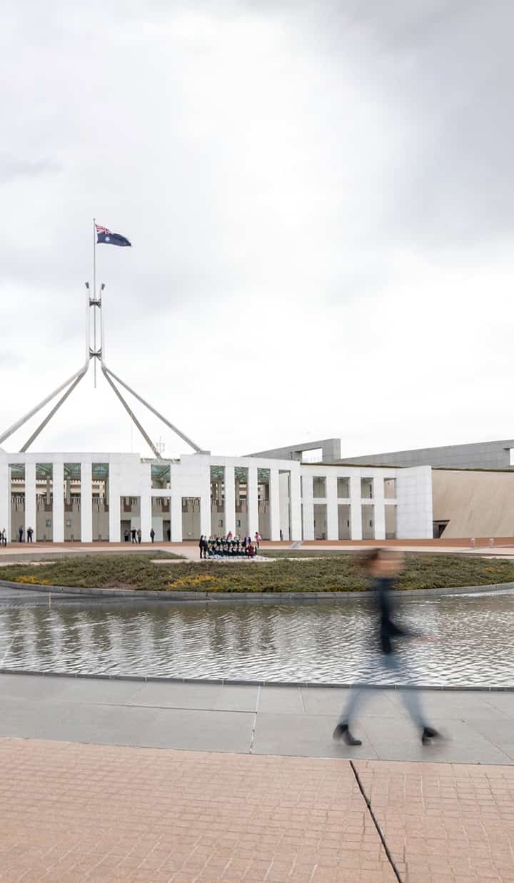 Blurred image of a person walking in front of Parliament House in Canberra
