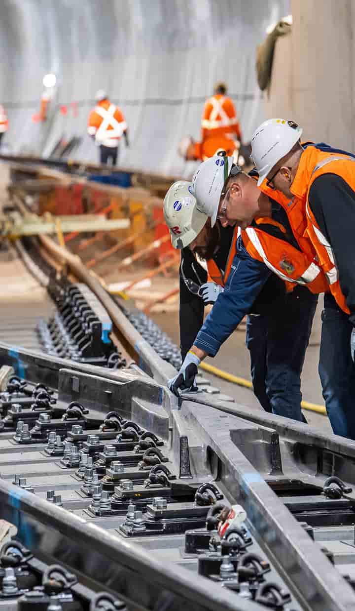 Construction workers inside a tunnel inspecting the rails of a metro system