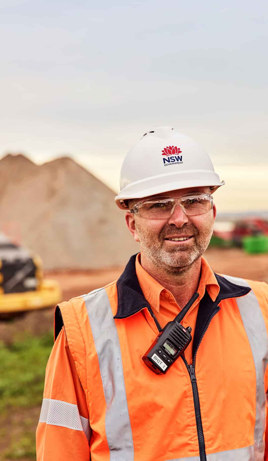 NSW worker on a construction site with a walkie talkie attached to their vest and wearing a PPE hat