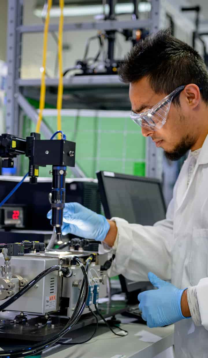 Scientist wearing sterile gloves and glasses analysing and preparing a sample on a microscope