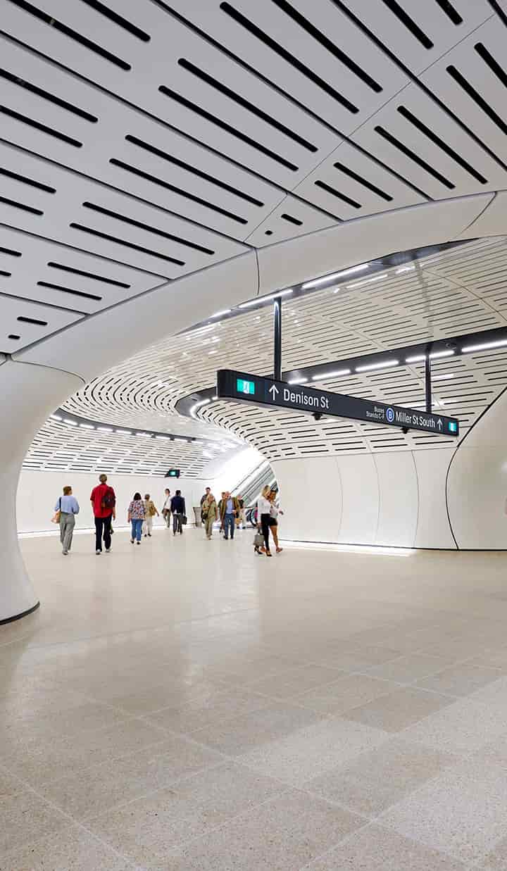 Train station exit to Denison St and directions to the bus station at Miller St, with commuters accessing the escalator