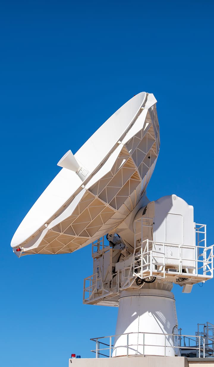 Large white satellite dish against blue sky.
