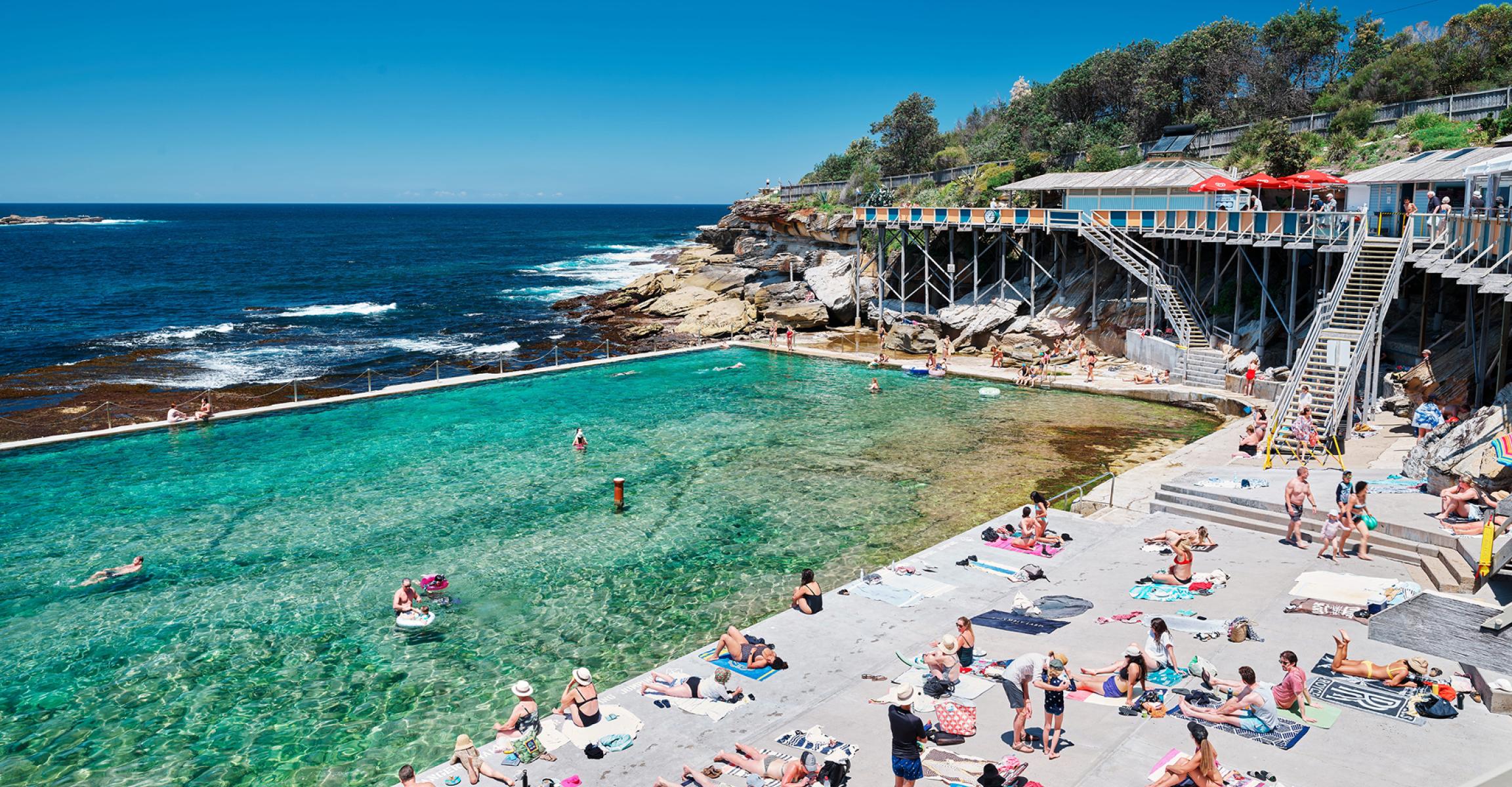 Swimmers and sunbathers relaxing at an ocean pool by the sea