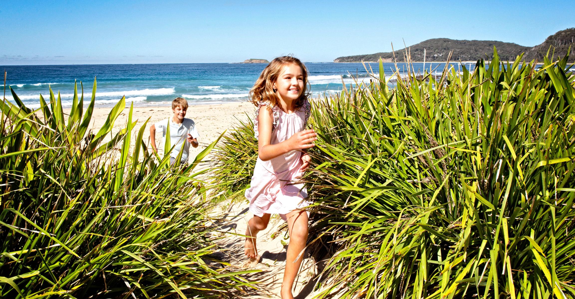 Two kids running on the beach at Pebbly Beach, South Coast, NSW, Murramarang National Park