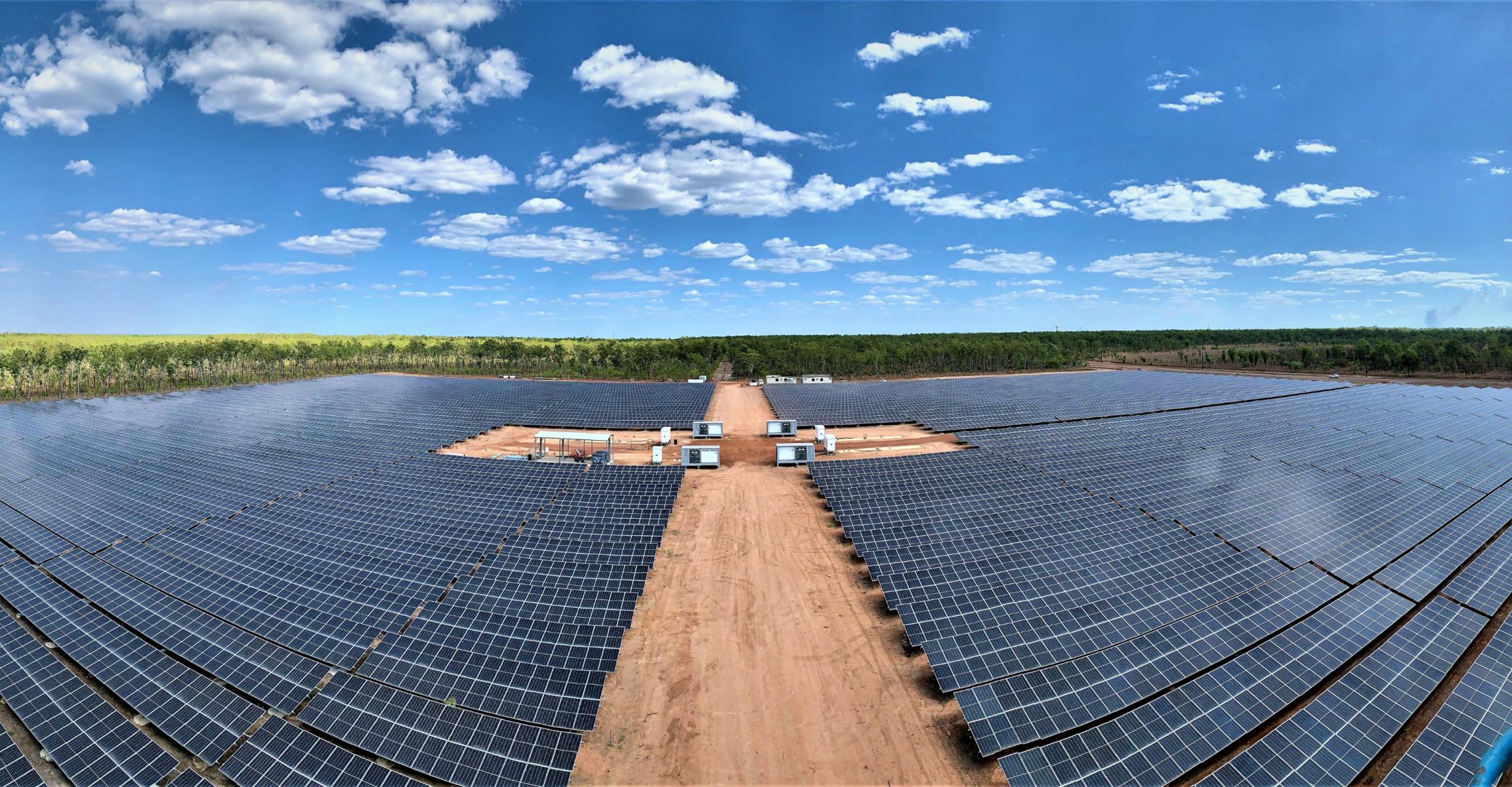 Expansive solar farm with solar panels and a bright blue sky overhead