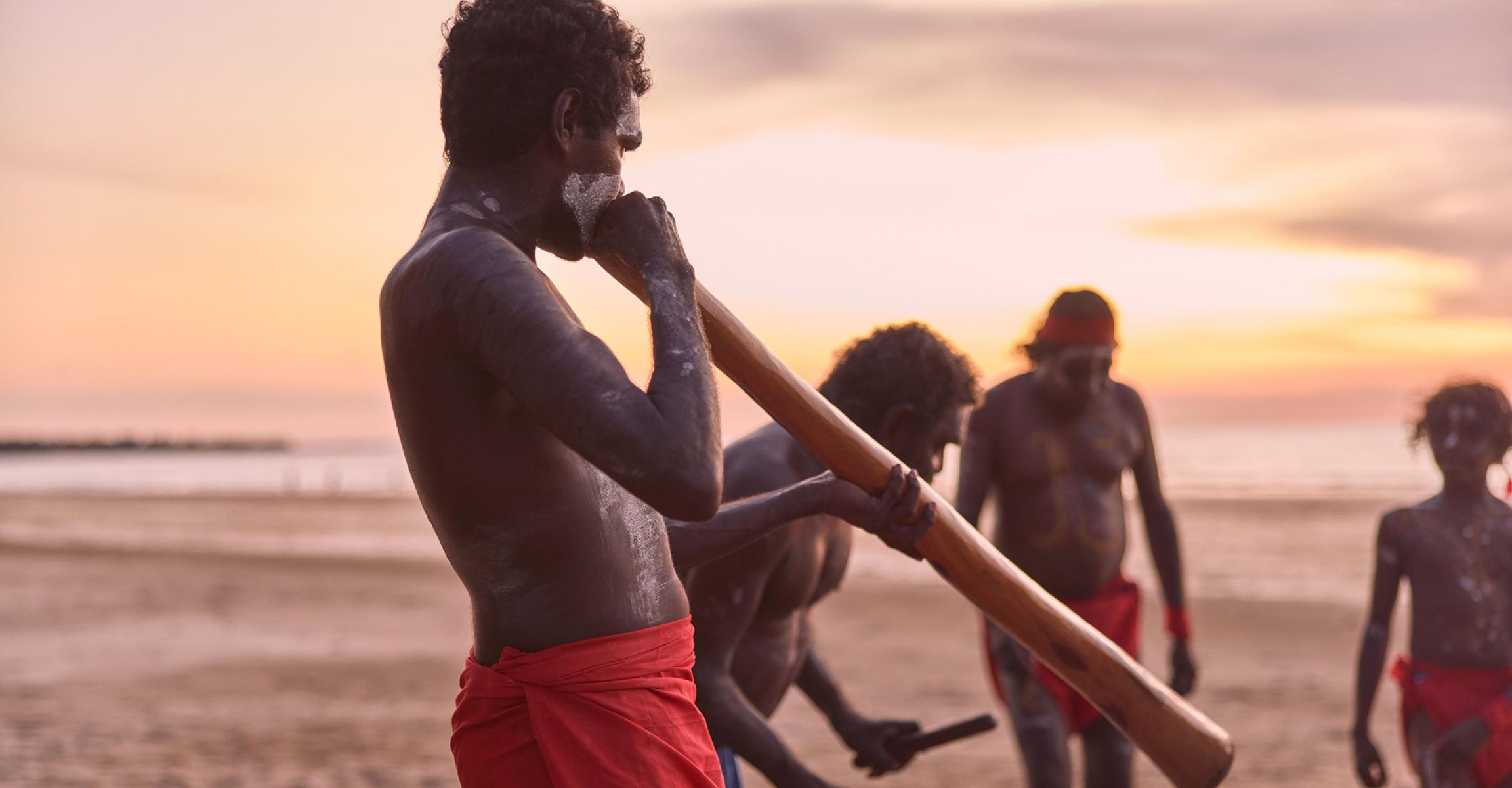 Group gathers at Casuarina Coastal Reserve to watch indigenous cultural performers at sunset