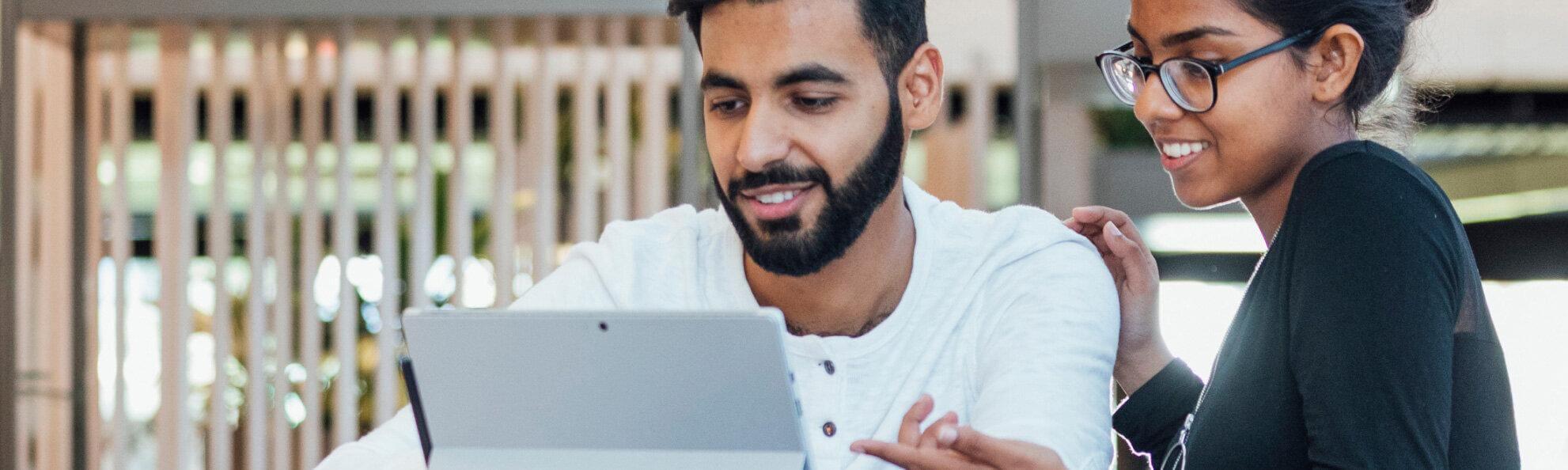 a young man and woman looking at a laptop screen